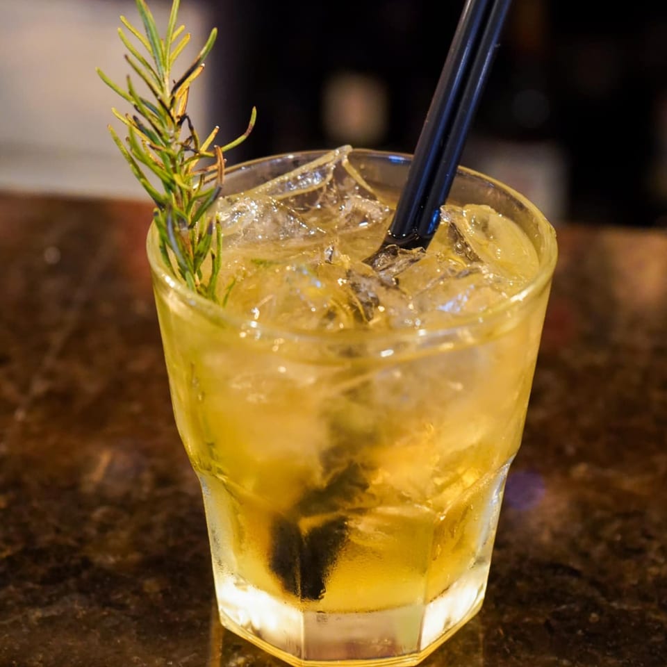 A refreshing iced drink with a rosemary sprig and black straw, served at Galloway Diner and Grill.