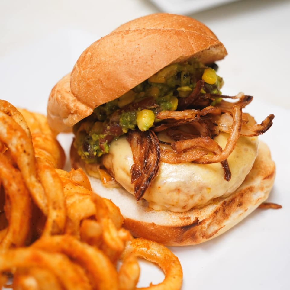 Galloway Diner's burger with melted cheese, guacamole, crispy onions, and curly fries.